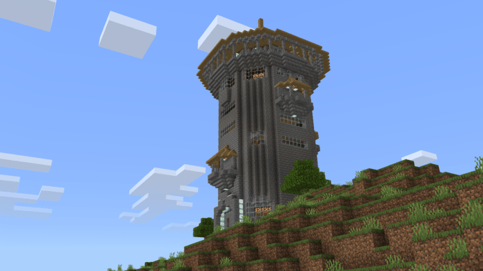 Tall stone tower on grassy hill.