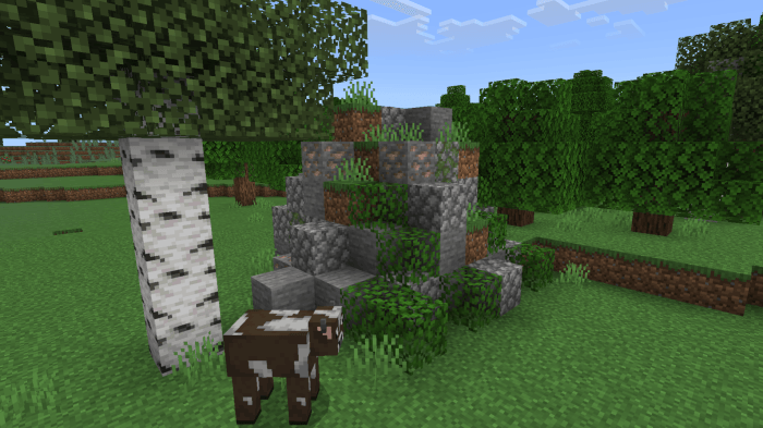 Cow near stone structure and birch tree.