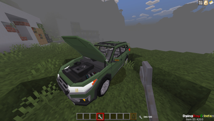 Green car with open hood in grassy area.