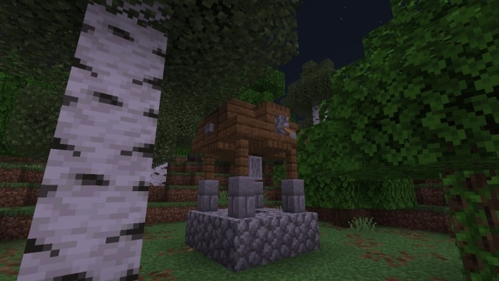 Wooden hut on stone pillars in forest.