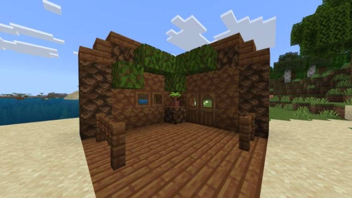 Wooden hut with plants on a sandy beach.