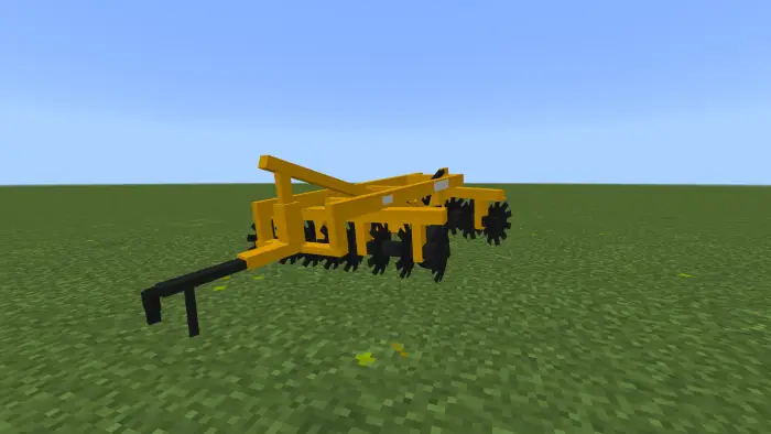 Yellow farming implement on grassy field