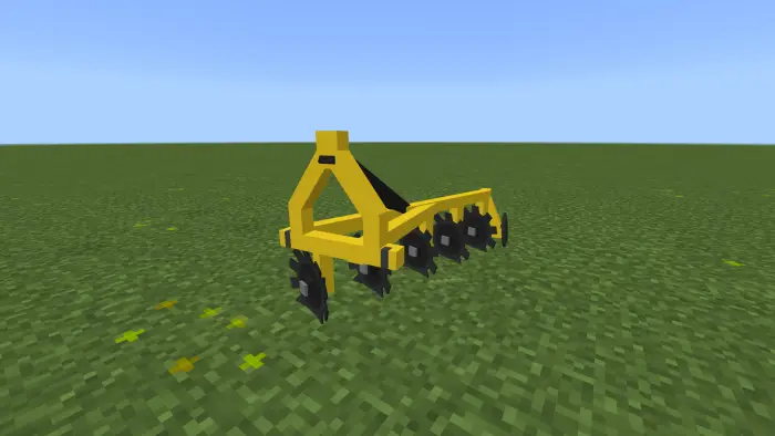 Yellow disc harrow on grassy farmland.