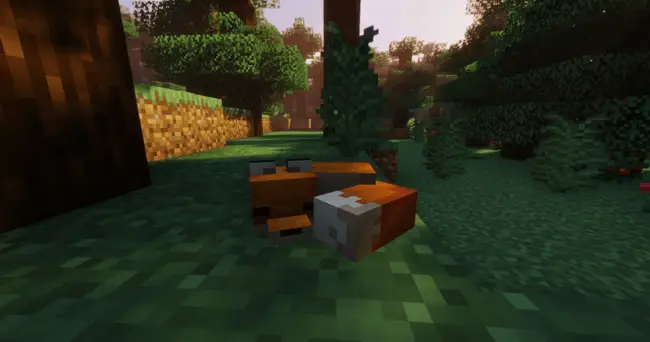Plush fox lying on grass in a forest.