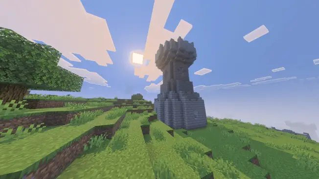 Stone tower stands on a grassy hillside.