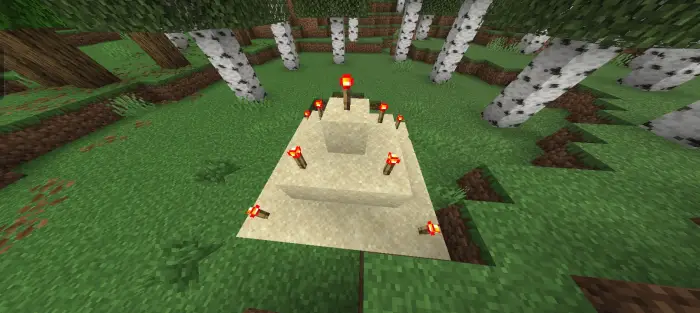 Sand pyramid with red torches in forest