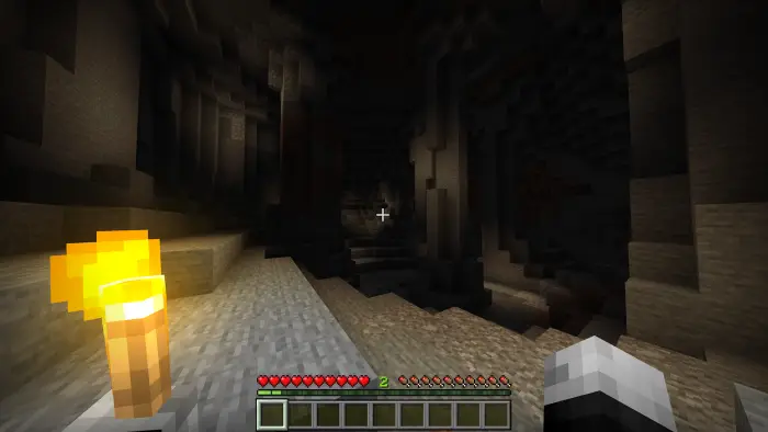 Player holding torch illuminates dark cave