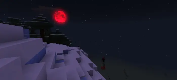 Red moon rises over snowy cliff at night.