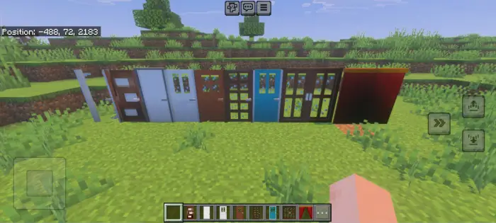 Row of various colorful doors on grass.