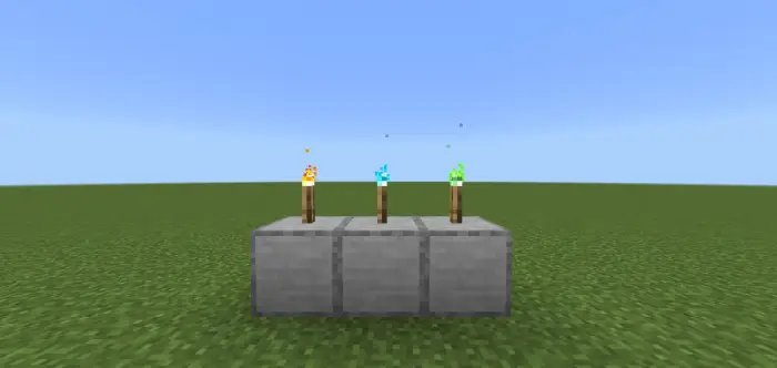 Tiga obor warna-warni di atas blok batu di luar ruangan