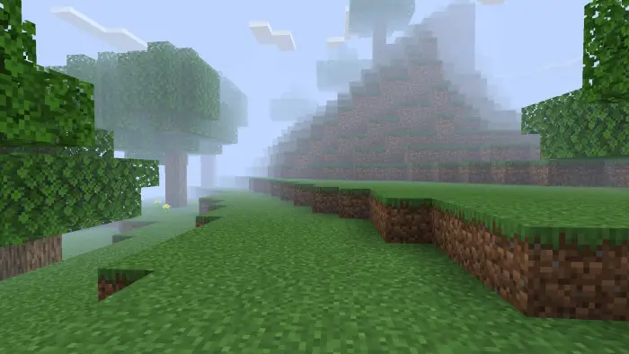 Blocky grassy terrain with fog and trees