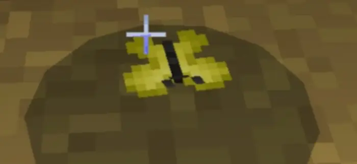 Pixelated yellow insect fossil in sand
