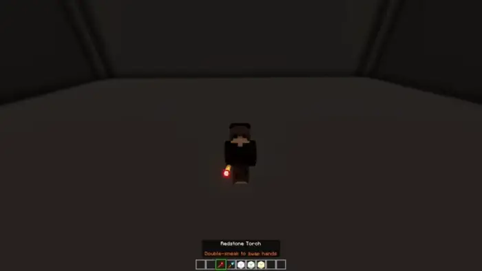 Player holds glowing redstone torch in hand