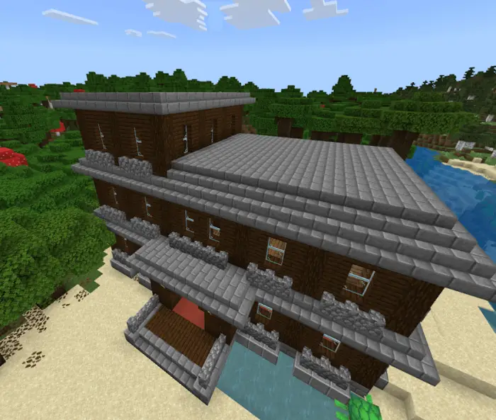 Large, dark mansion with stone roof by forest.