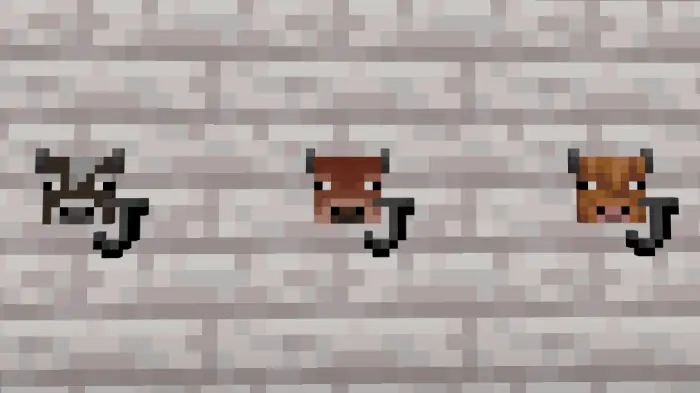 Three pixelated cow heads on a stone wall