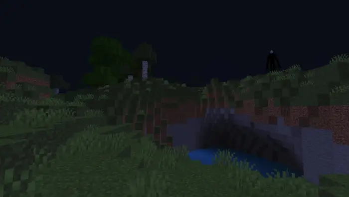 Black entity with white face on grassy hill
