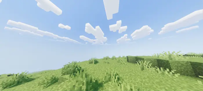 Bright grassy field with soft clouds above