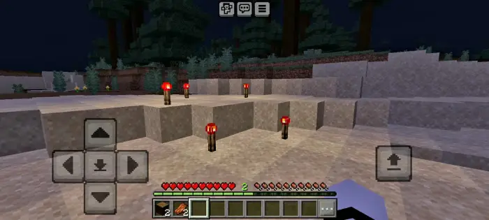 Redstone torches lighting a sandy terrain at night