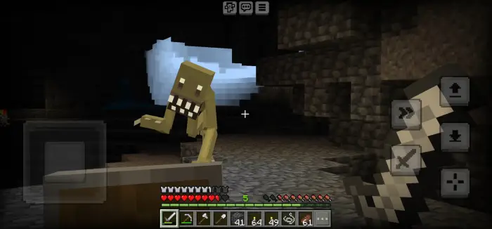 Player faces Cave Dweller mob in a dark cave.
