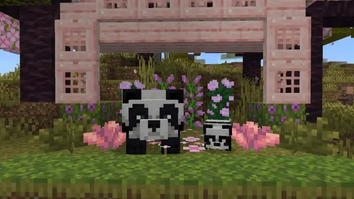 Two pandas in a garden under a pink arch.