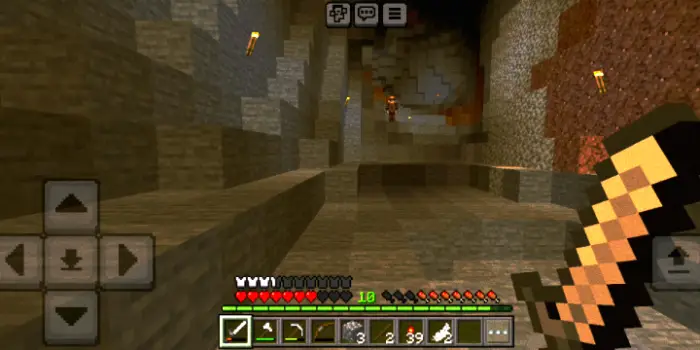Player explores a dark, torch-lit cave.