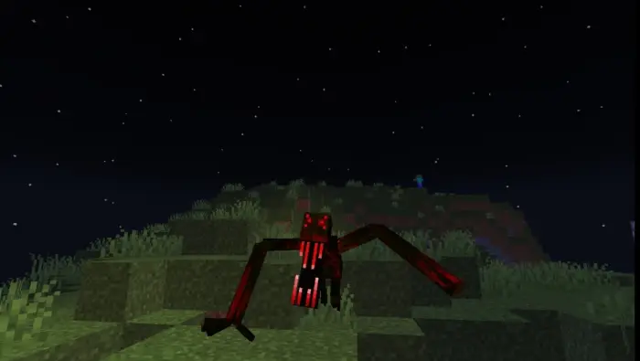 Red, spider-like creature on grassy hill at night
